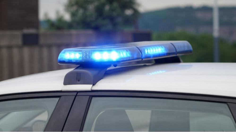 Close up view of white car roof with blue lights on top.
