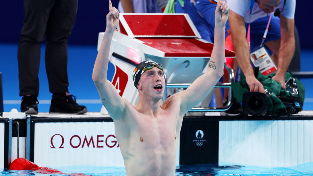 Daniel Wiffen in the swimming pool with his arms raised after winning the Olympic gold 