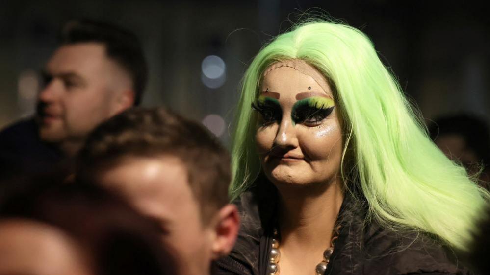 Image shows a person in the crowd during a vigil for James Lee Williams, popularly known as The Vivienne, in Liverpool, Britain, on 12 January, 2025