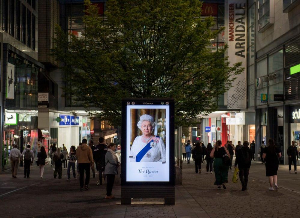 A digital advertising board on Market Street in Manchester shows an image of Queen Elizabeth II