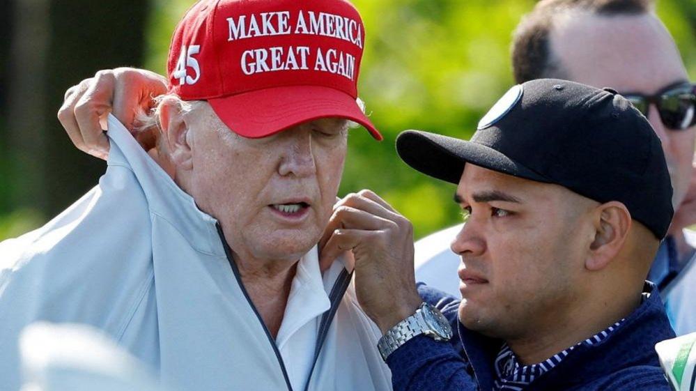 Walt Nauta rearranges Donald Trump's collar at the Trump National Golf Club in Sterling, Virginia, on 25 May, 2023.