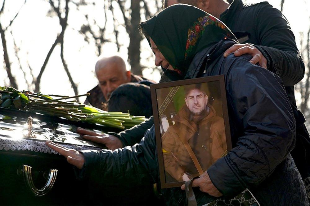 Mother clutches a portrait of her soldier son