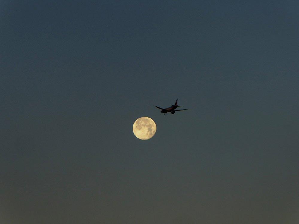 An aeroplane in front of the moon