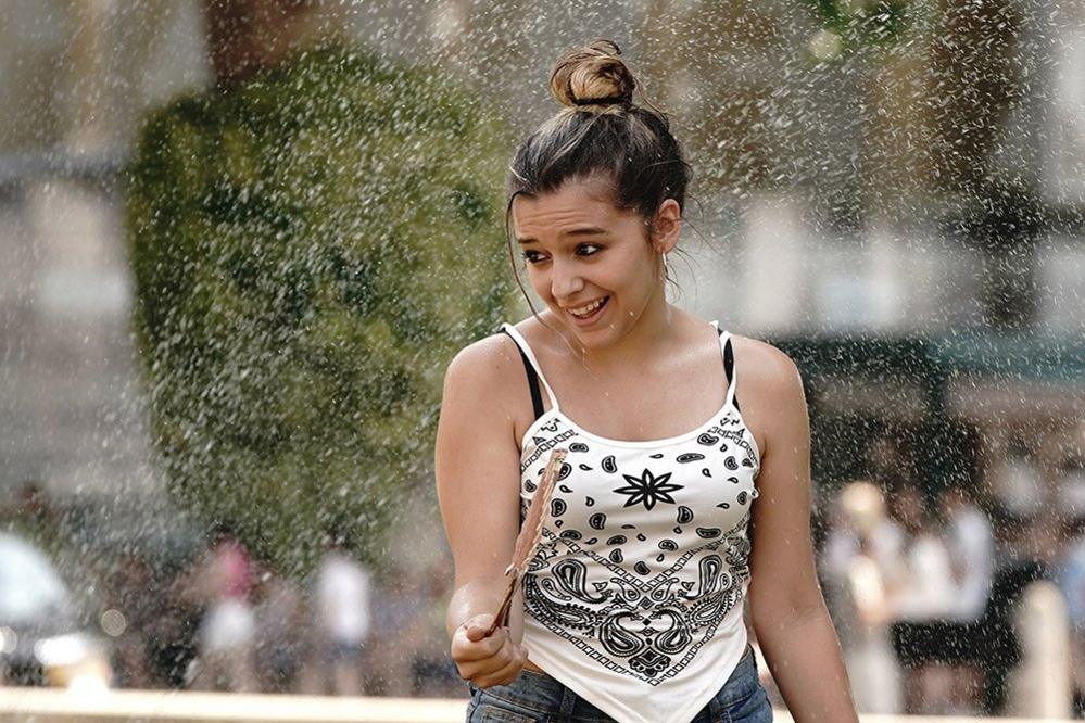 A person standing under a water sprinkler outside Queen Elizabeth II Centre in central London