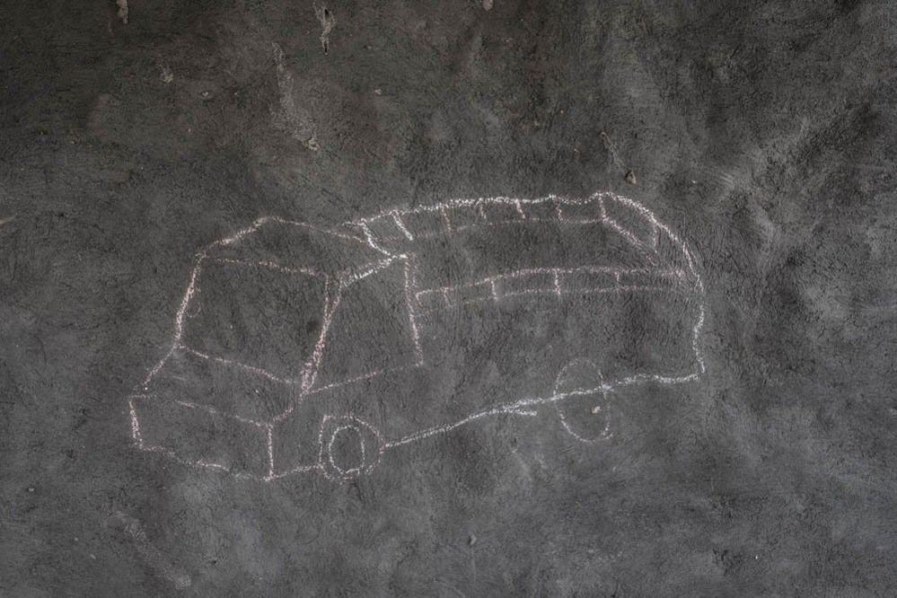 A drawing of a truck adorns the mud wall of a refugee shelter