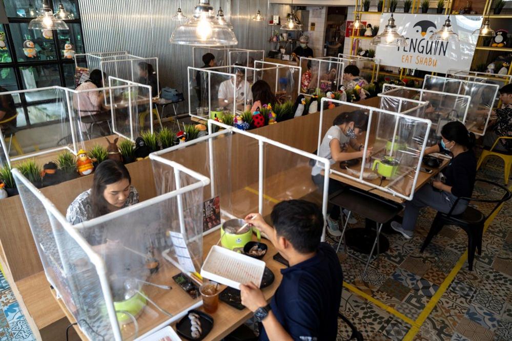 People eat in a restaurant with clear plastic barriers between diners