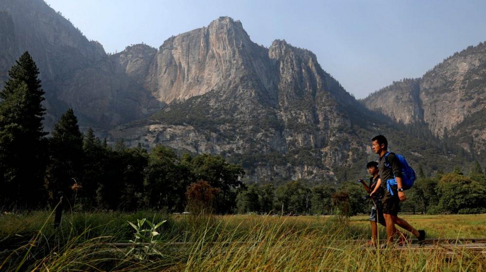 Visitors walk past Columbia Rock in Cook's Meadow in Yosemite Valley, Yosemite National Park