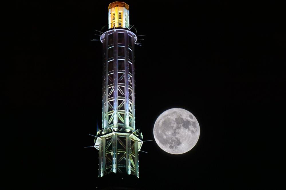 A full moon rises behind the Canton Tower on July 3, 2023 in Guangzhou, Guangdong Province of China