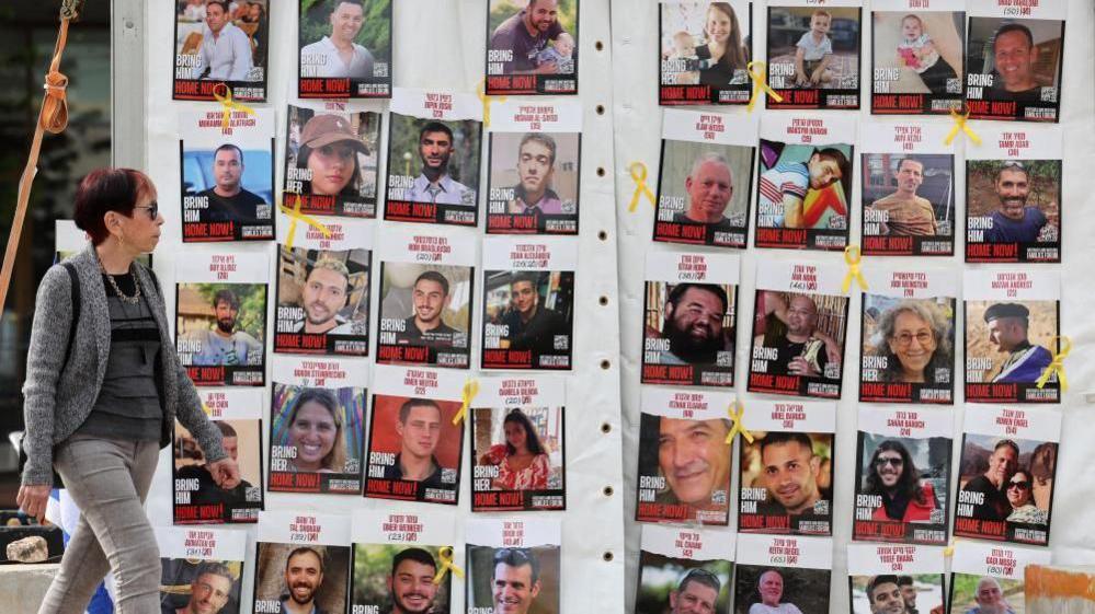 A woman walking past a display of Israeli hostage posters