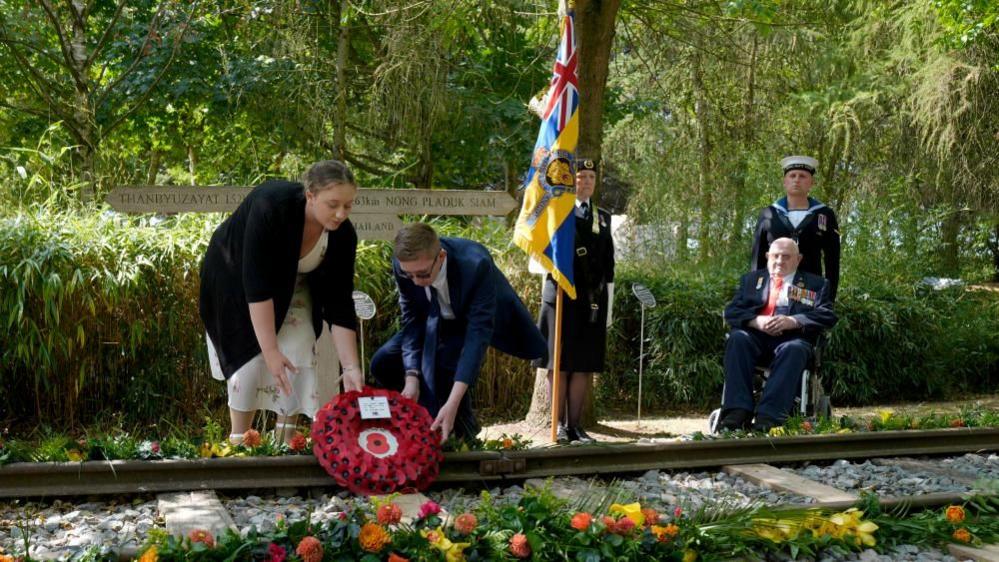 Second World War veteran Alfred Conway (right) from Lincolnshire, who served with the Royal Navy, watches on as his great-grandchildren, Sarah-Jayne Carpenter (left) and James Carpenter (second left) lay a wreath on the Burma Thailand Railway memorial at the National Memorial Arboretum