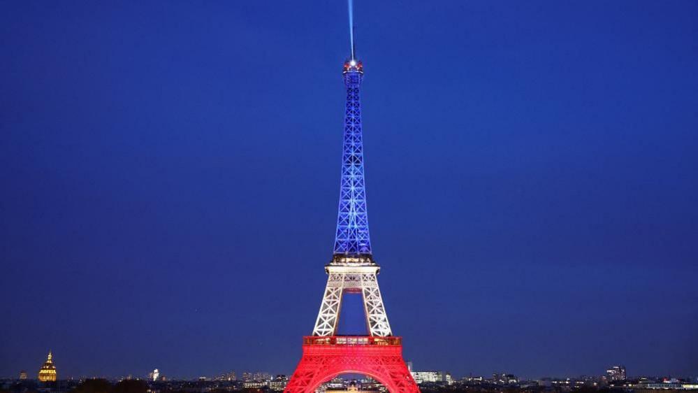 The Eiffel Tower is lit up with the blue, white and red colours of the French flag to mark the tenth anniversary of the November 13 Paris attacks