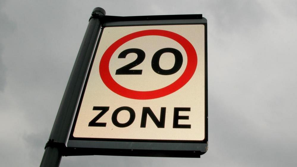 Close-up image of a 20mph zone sign, against a cloudy background.