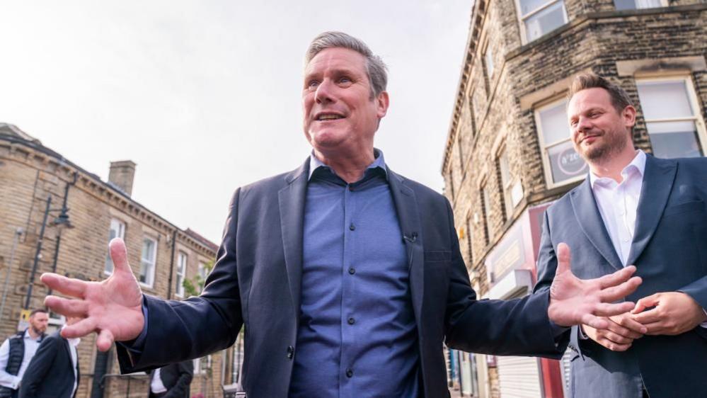 Sir Keir Starmer with arms spread stands next to Simon Lightwood after he was elected as Wakefield MP