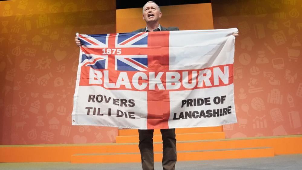 Former party leader Tim Farron holding a Blackburn Rovers 'Pride of Lancashire' flag during a rally at the Liberal Democrats autumn conference