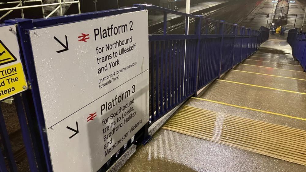 A sign at a medium-sized railway station reading "Platform 2 for Northbound trains to Ulleskelf and York, Platform 3 for Southbound trains to Leeds, Bradford, Halifax and Manchester Victoria".