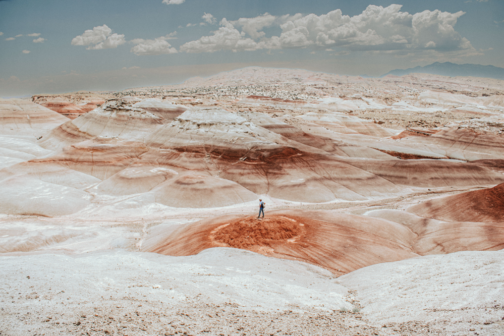 walker in the red streaked Bentonite Hills, a remote hiking area in Utah, USA.