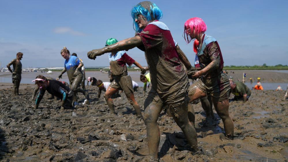 Competitors take part in the annual Maldon Mud Race, a charity event to race across the bed of the River Blackwater in Maldon, Essex