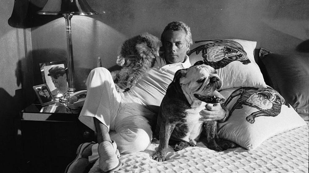 Giorgio Armani poses on a bed with his cat and dog