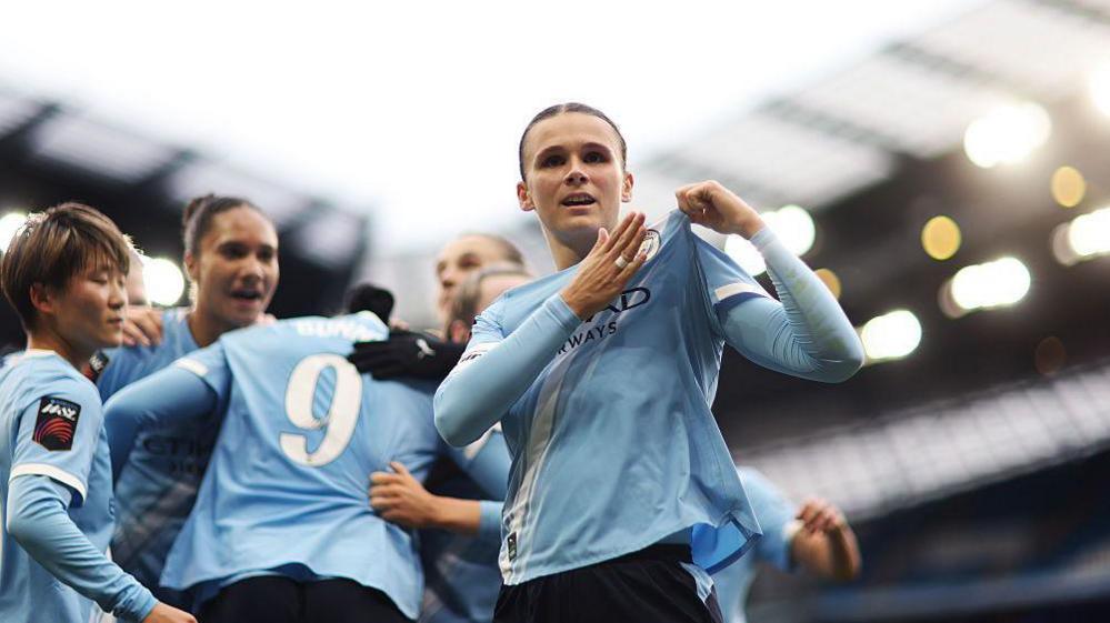 Kerstin Casparij points to her Manchester City badge