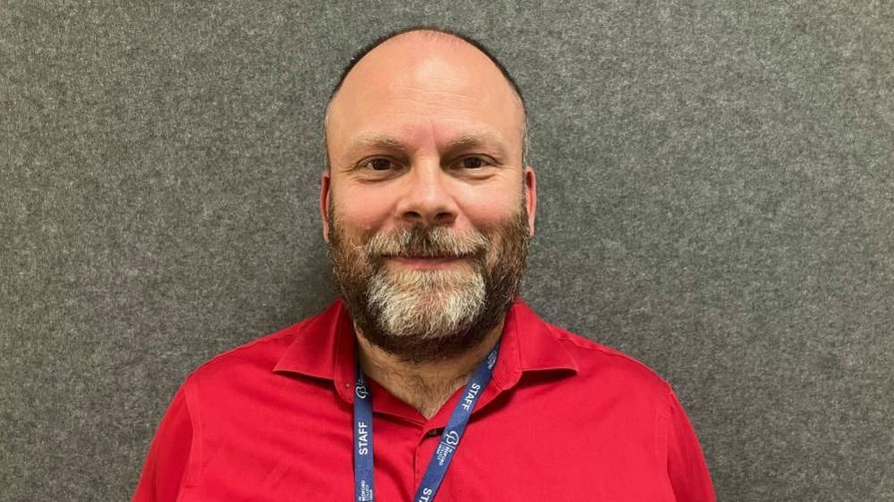 Mark Tinney wearing a red shirt and a blue lanyard