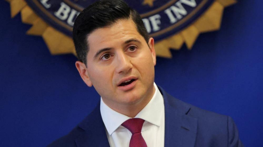 United States Attorney Bill Essayli stands in front of an FBI logo