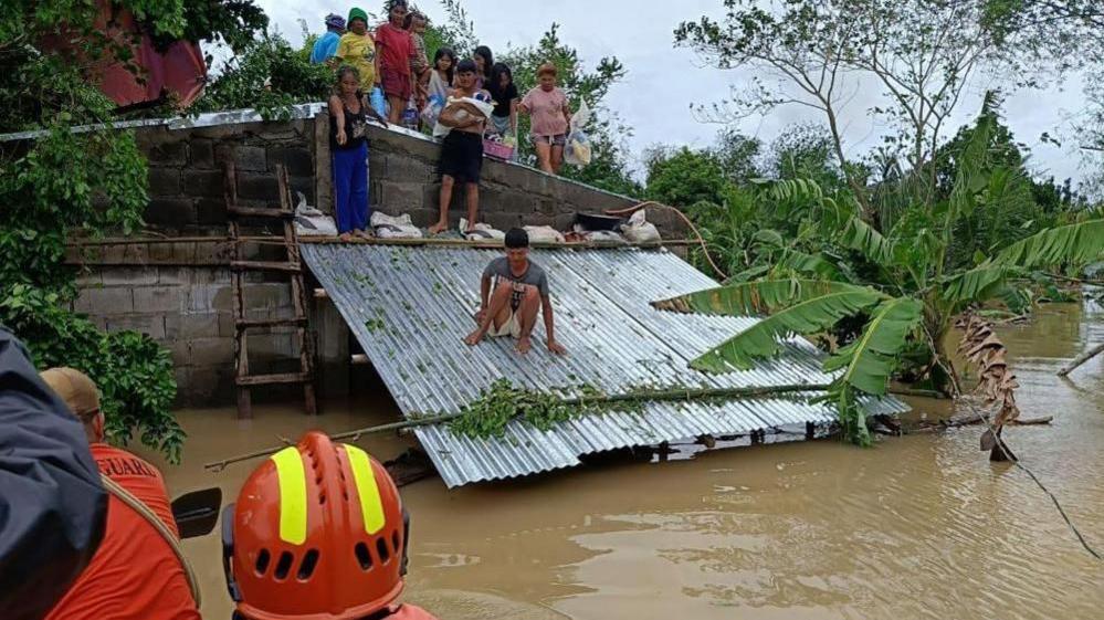 Coastguard personnel rescuing villagers on the roof of their flooded home in Libon town