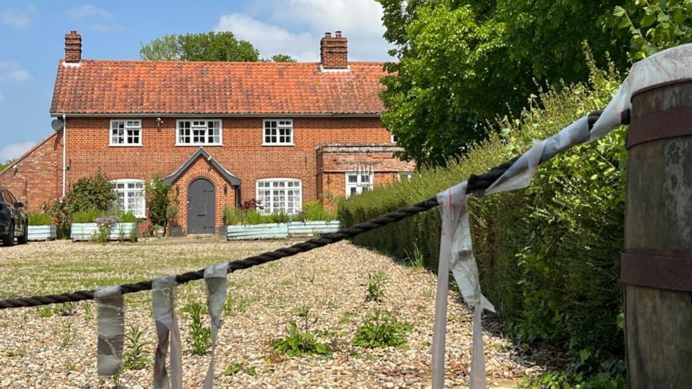 Brick-built two-storey pub with gravel drive and rope across entrance