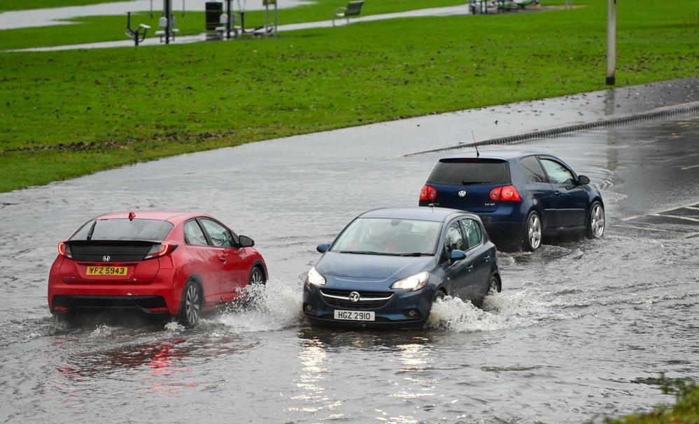 Three hatchback cars driving through flood water 