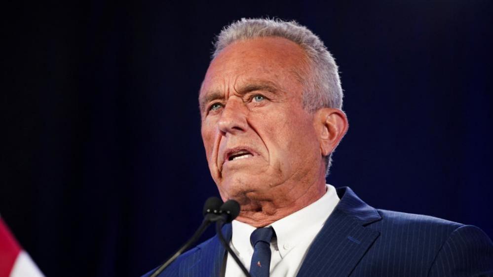 Robert F Kennedy Jr speaking in Phoenix, Arizona, US on 23 August, 2024. He is wearing a navy pinstripe suit and a navy tie.