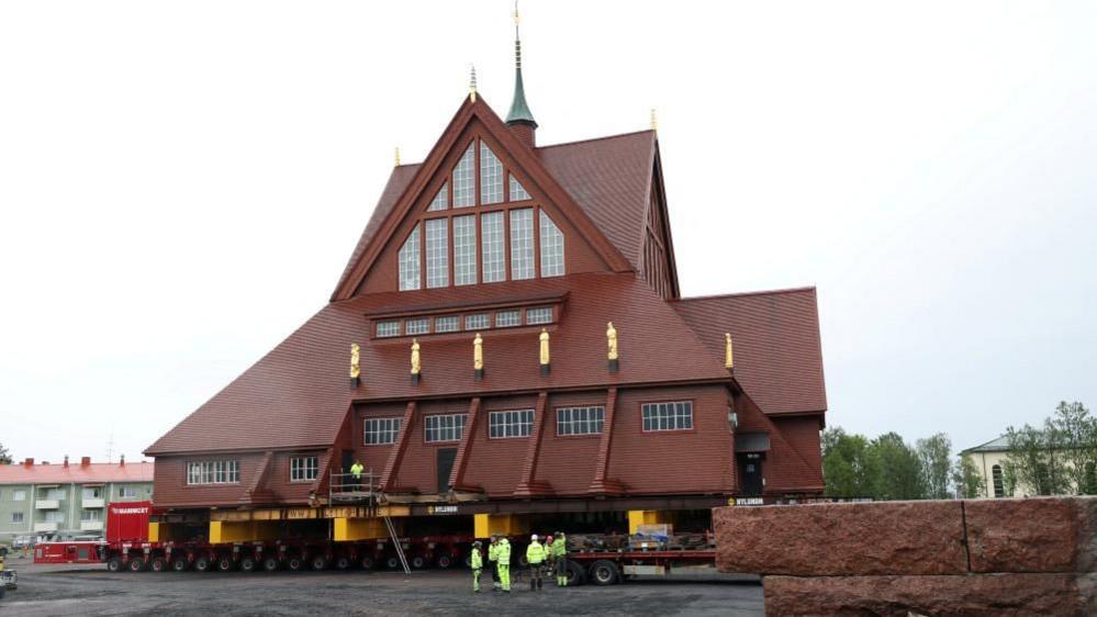 Kiruna's historic wooden church sits on a wheeled transportation unit before being moved to a new site in Kiruna, Sweden