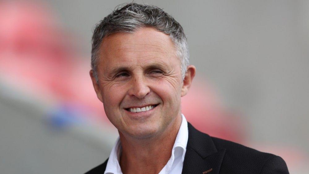 Paul Rowley smiles in his shirt and suit jacket before a Salford game