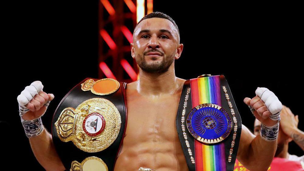 Callum Simpson posing with the British and Commonwealth belts