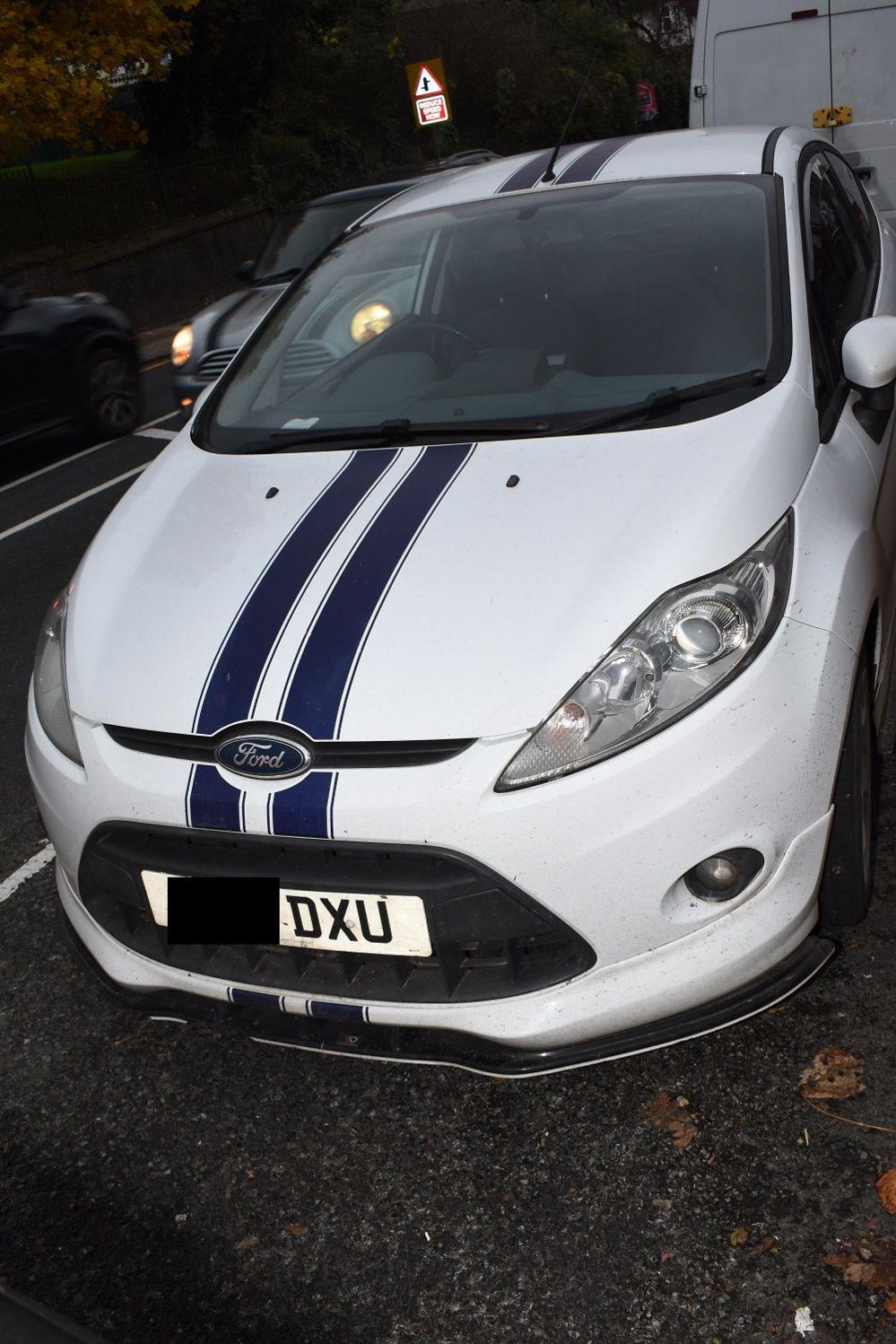 A white Ford Fiesta with blue stripes