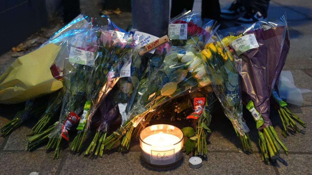 Flowers and candles left in a group on a pavement