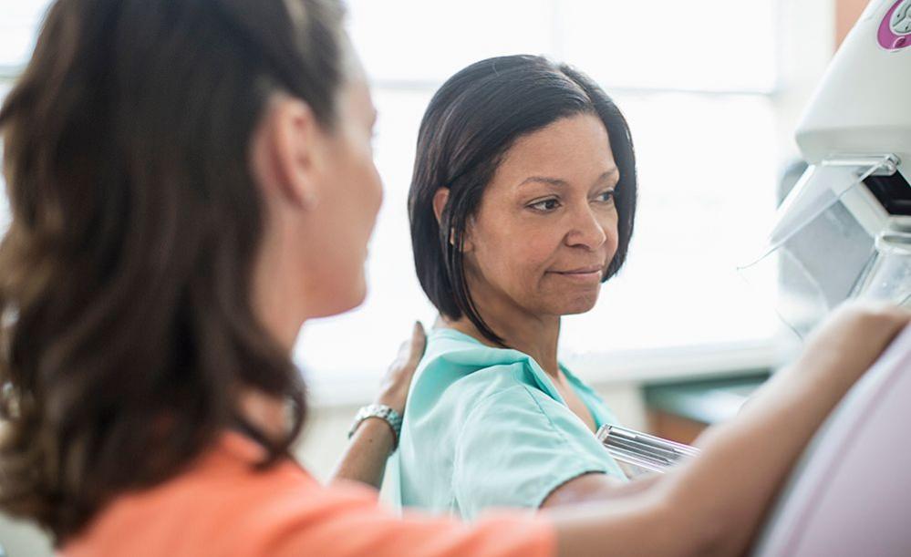 A woman is helped by a nurse while getting a mammogram done