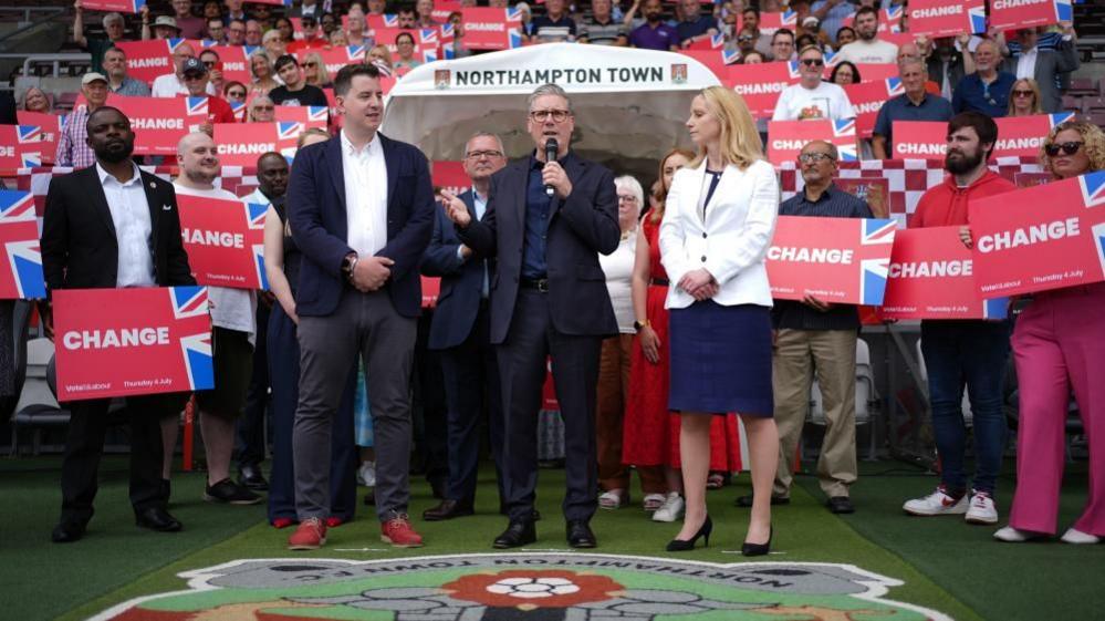 Keir Starmer with microphone surrounded by supporters with red placards