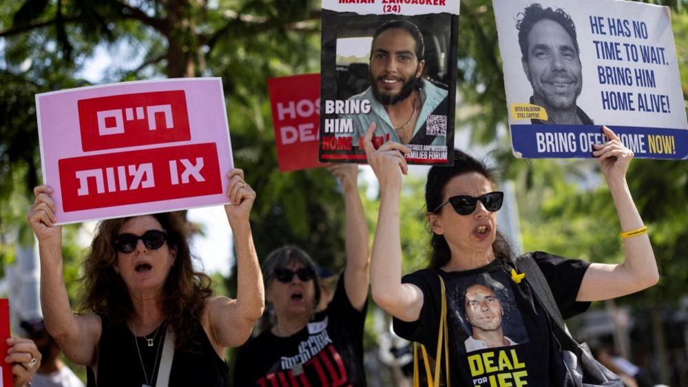 Families of Israeli hostages held by Hamas hold up placards at a protest calling for their release in Tel Aviv 