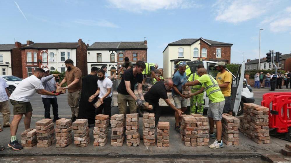 Volunteers rebuild the fence outside Southport Islamic Society Mosque, after a violent protest, following a vigil for victims of the knife attack