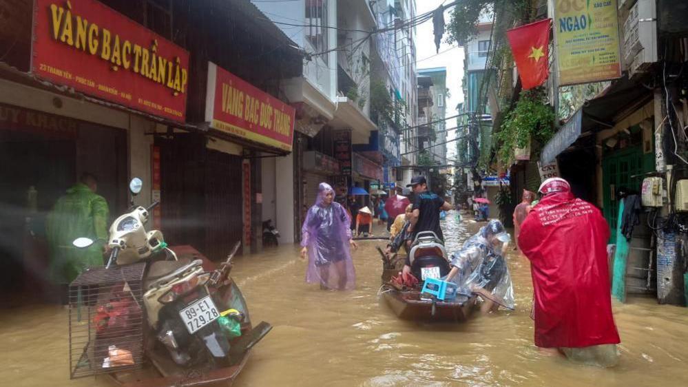 People wade through a flooded street following the impact of Typhoon Yagi, in Hanoi, Vietnam