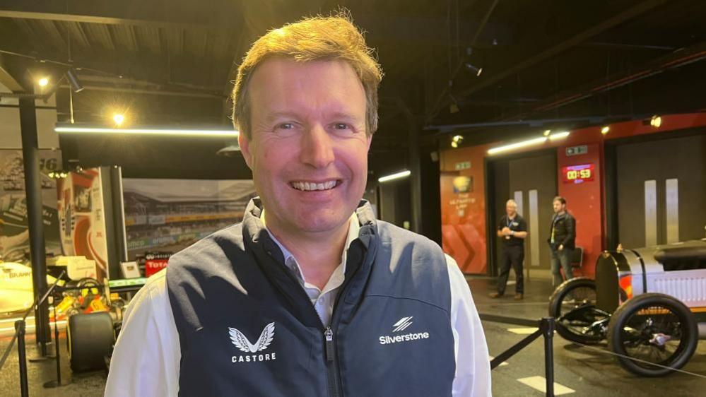 Stuart Pringle in a shirt and gilet looking at the camera and smiling