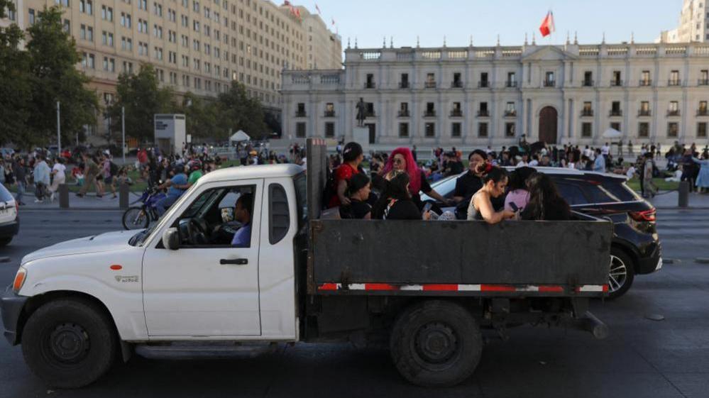 People ride on the back of a vehicle amid a large power outage, in Santiago, Chile February 25, 2025