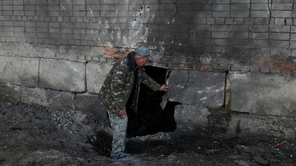 A resident inspects his apartment building hit by a Russian drone strike, amid Russia's attack on Ukraine, in the village of Krasylivka, Chernihiv region, Ukraine, 3 November 2024