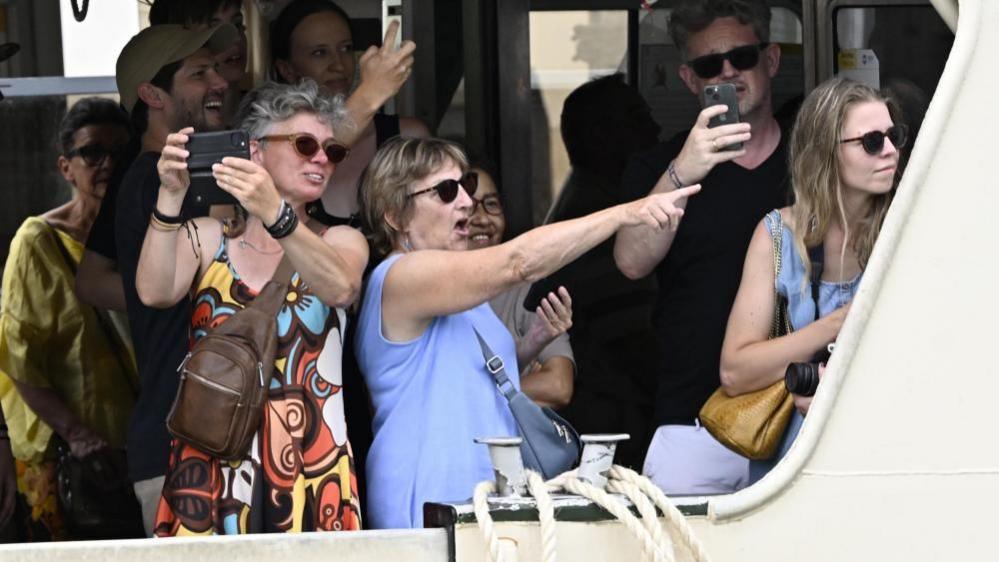 Onlookers point their cameras toward Jeff Bezos (not pictured) and guests, spotting them from a boat in Venice.