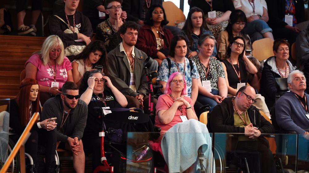 People sit in staggered seating in a public gallery in the Scottish parliament