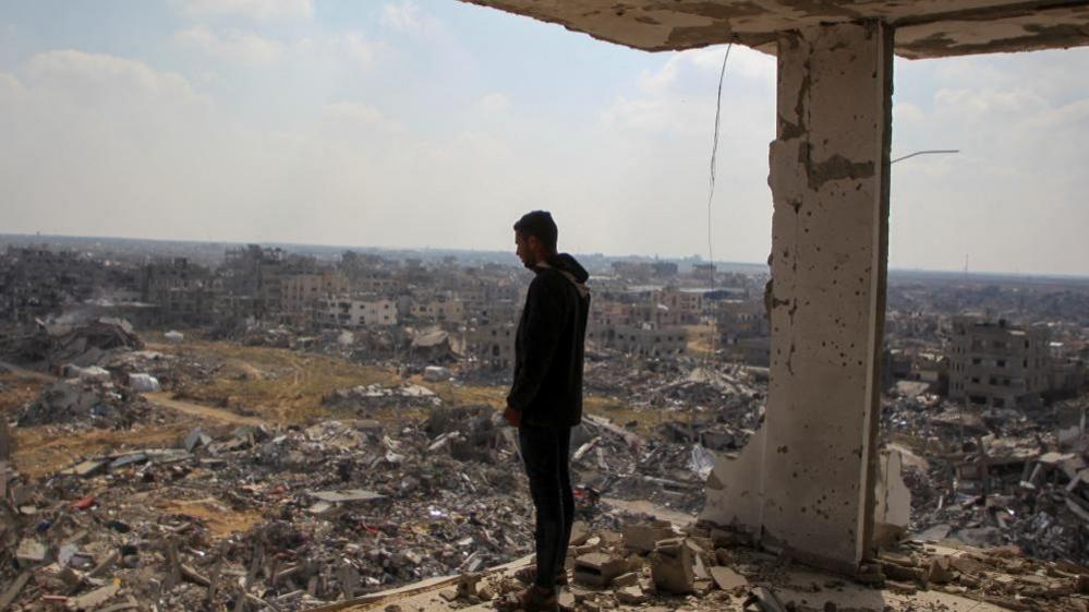 A Palestinian man standing in the ruins of a building