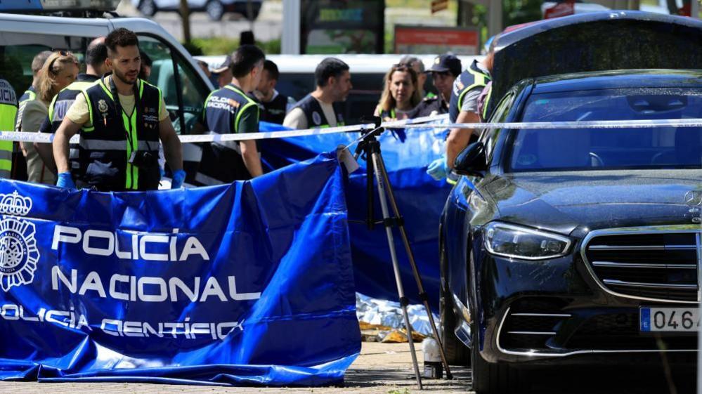 Police officers stand near the car of ex-Ukraine MP Andriy Portnov after he was shot dead outside a school in Madrid