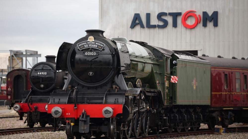  'The Flying Scotsman' on display during 'The Greatest Gathering' railway festival in Derby. The black and green steam locomotive is in front of "Alstom" building.