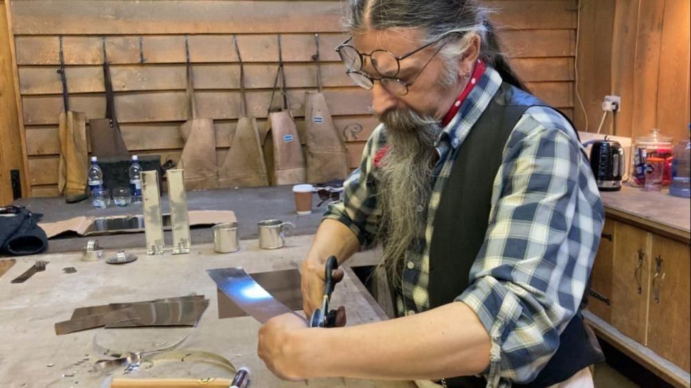 John Wills with a cutter in one hand and tin plate in the other