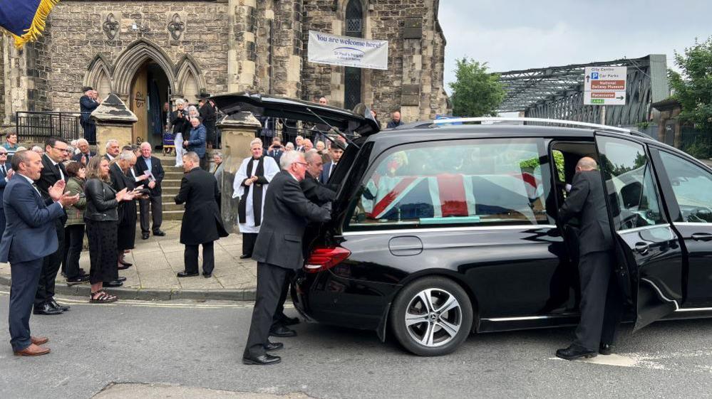 Congregation applauds coffin