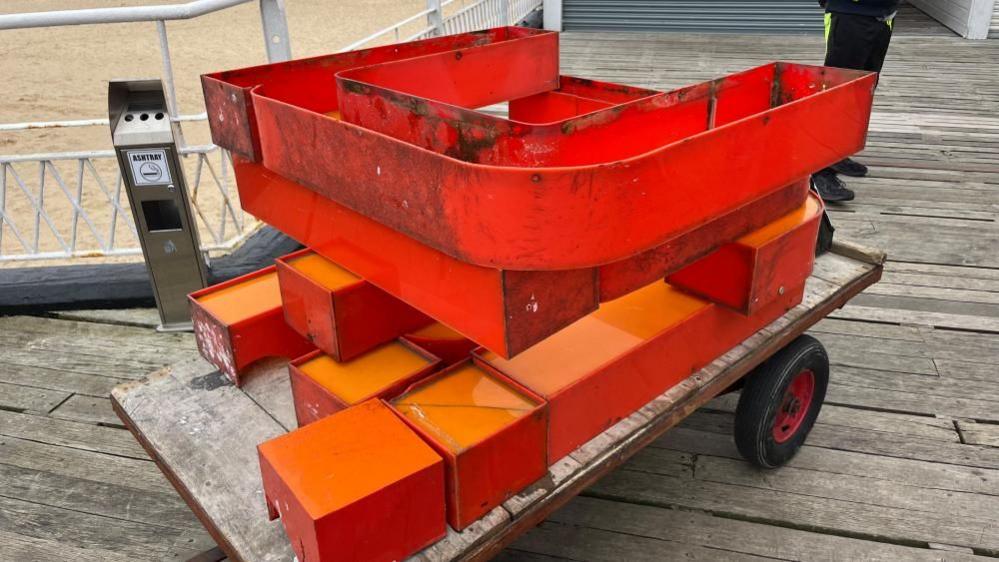 Orange-coloured letters from the Britannia Pier signage on a barrow being taken off site.